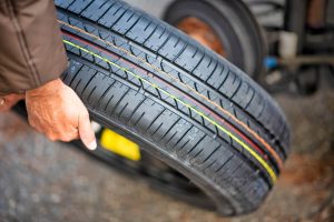 Young man changing the punctured tyre on his car - NOLA Automotive Repairs
